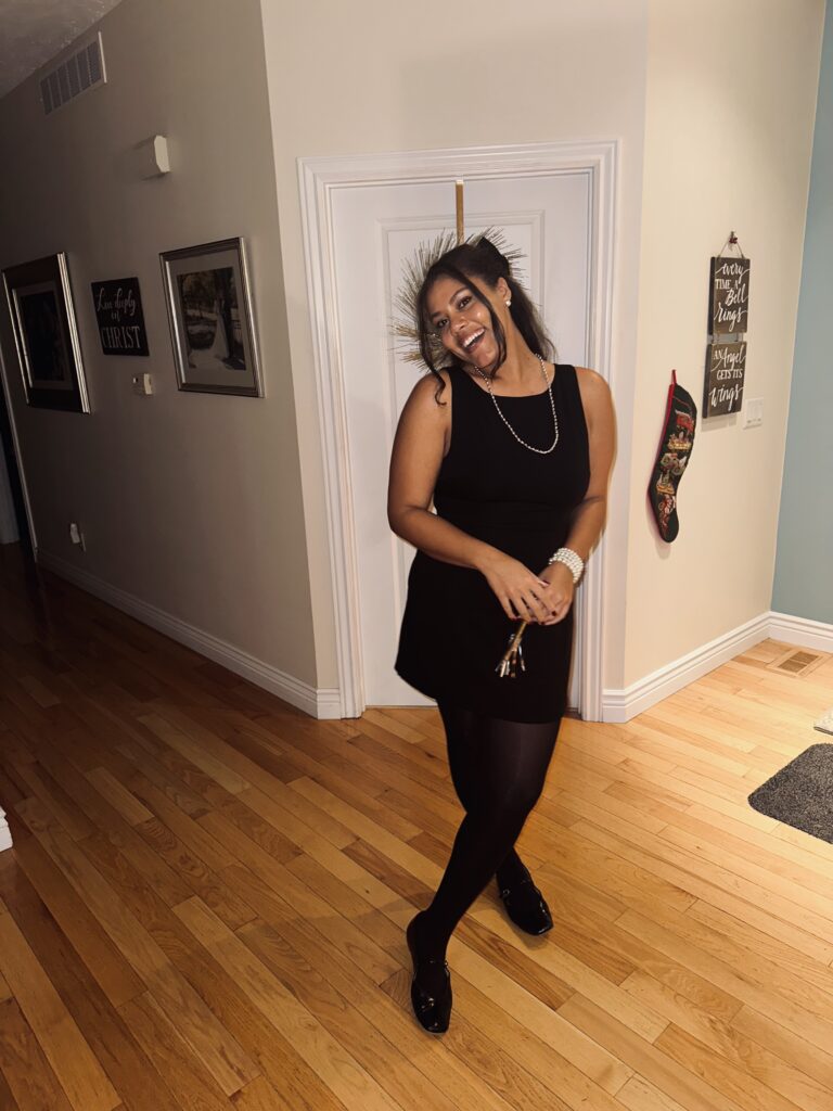 model wearing little black dress with tights and black ballet flats. 